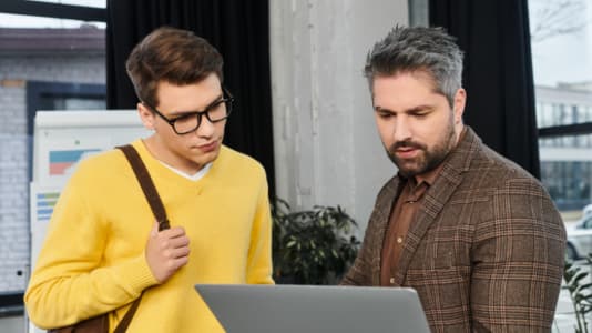 Två män som samtalar vid en laptop