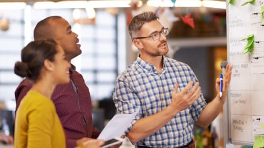 Tre personer vide en whiteboard