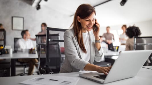 Smiling woman with phone and laptop